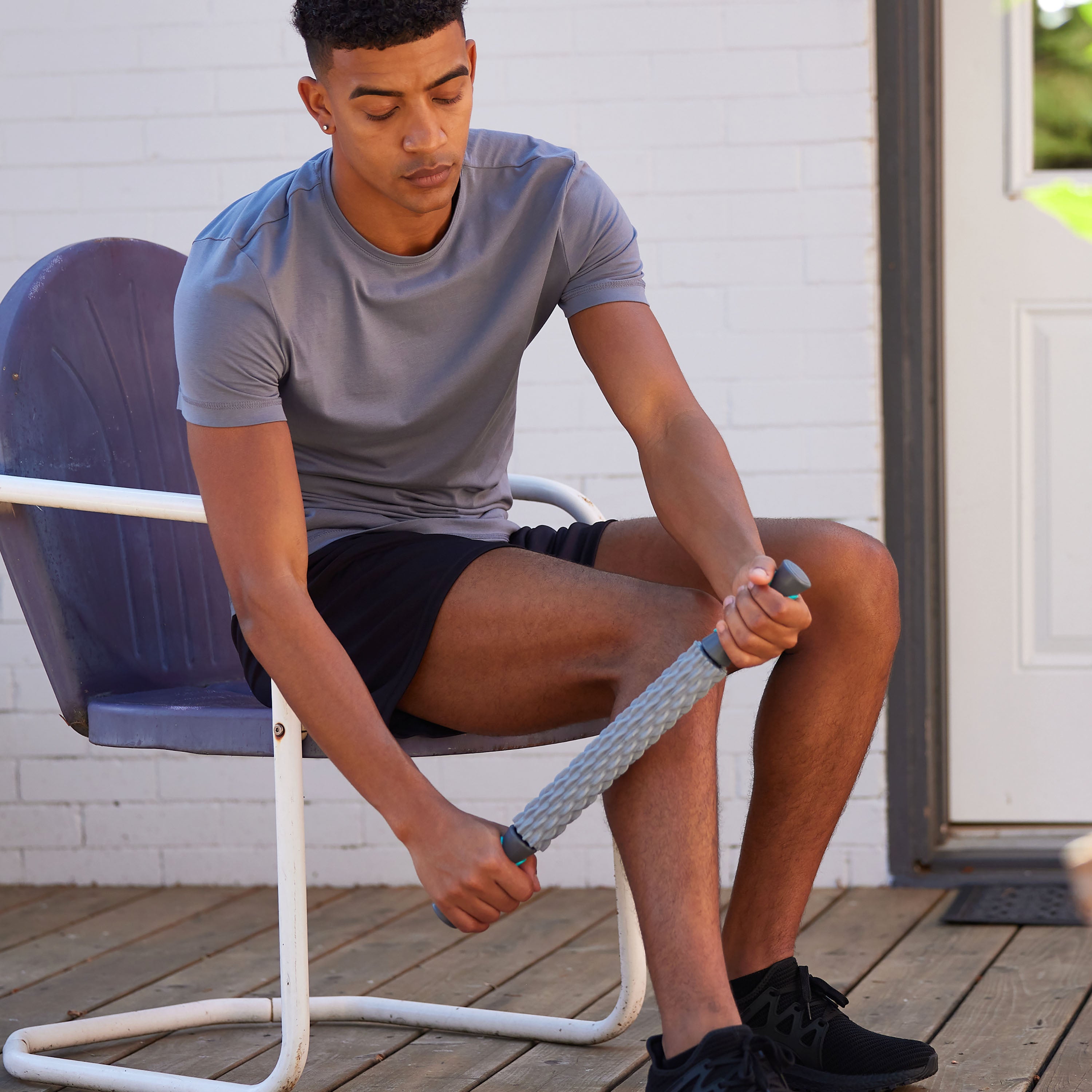 Seated Person using the Restore Deep Tissue Massage Roller on the side of the calf muscle